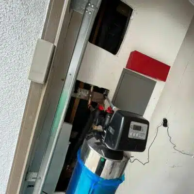 Water softener system installed in a garage with exposed wall cutouts